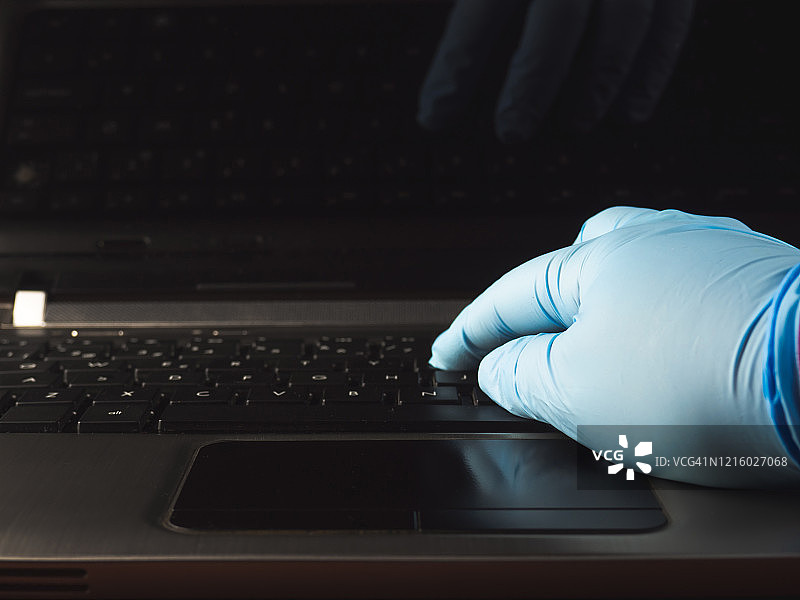 在家使用笔记本电脑和丁腈防护手套工作的人图片素材