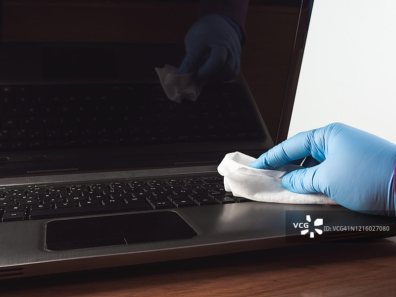 在家工作的人用抹布和丁腈防护手套清洁笔记本电脑图片素材