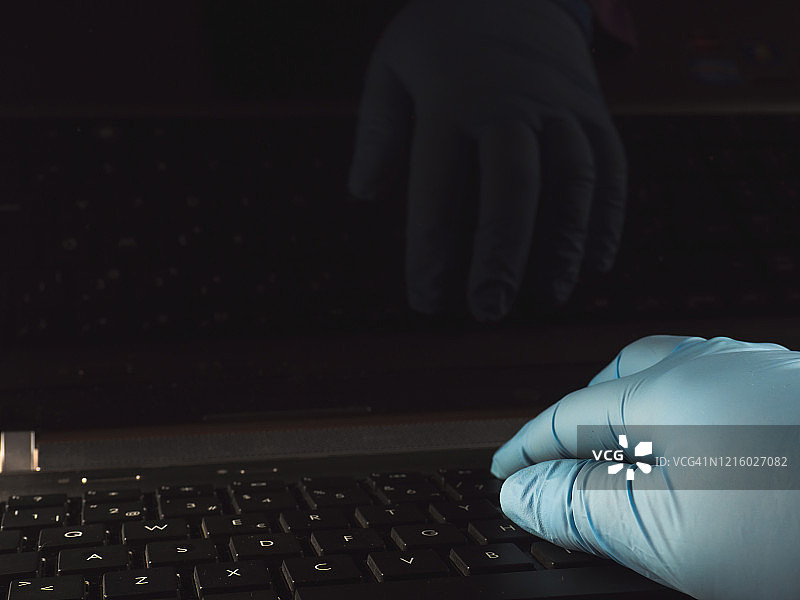 在家使用笔记本电脑和丁腈防护手套工作的人图片素材