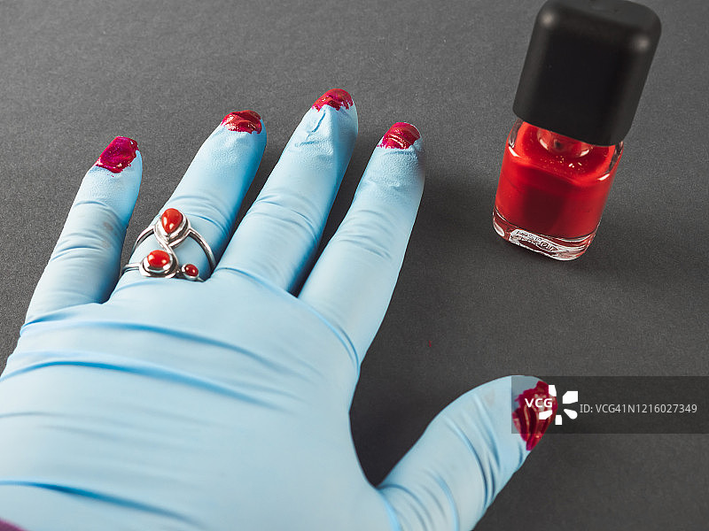 一个人戴着腈纶防护手套，用红色珐琅油漆涂指甲图片素材