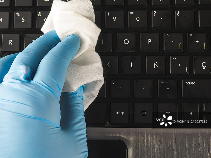 在家工作的人用抹布和丁腈防护手套清洁笔记本电脑图片素材