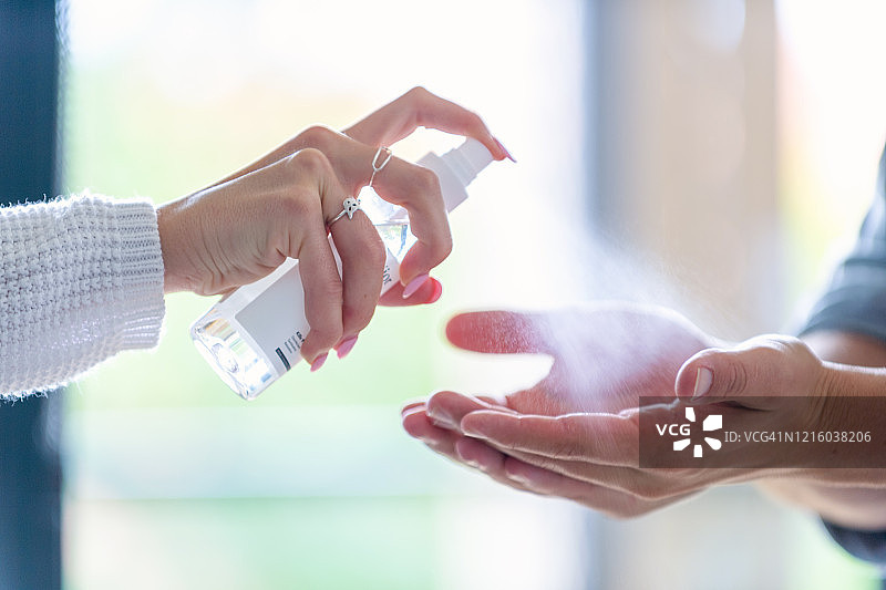 女人往男人手上喷洒洗手液图片素材