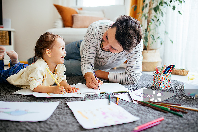 年轻的父亲和女儿一起快乐地画画图片素材