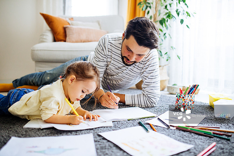年轻的父亲和女儿一起快乐地画画图片素材