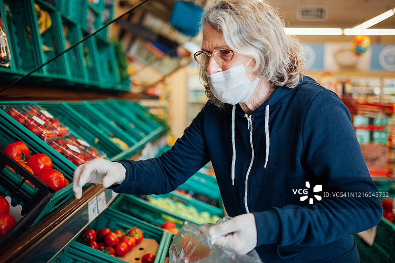 中年妇女戴着防护口罩在杂货店购物图片素材