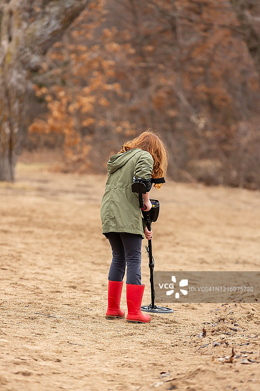 在沙滩上使用金属探测器的年轻女孩图片素材