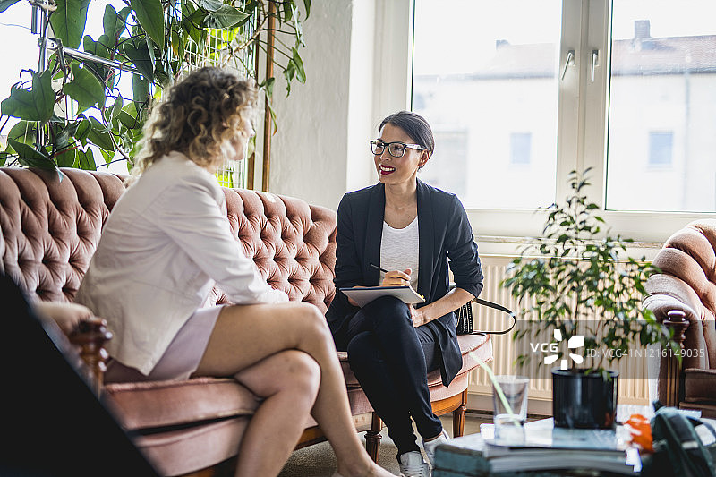 在混合办公室空间里交谈的年轻女商人图片素材