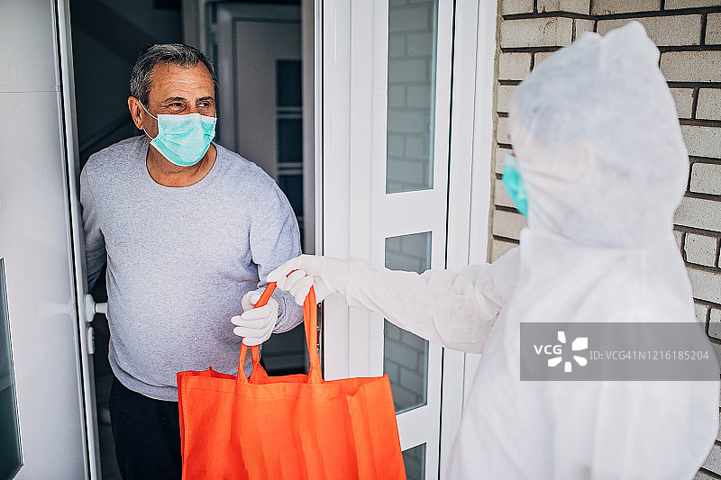 世界卫生组织志愿者为老年男人送食品杂货图片素材