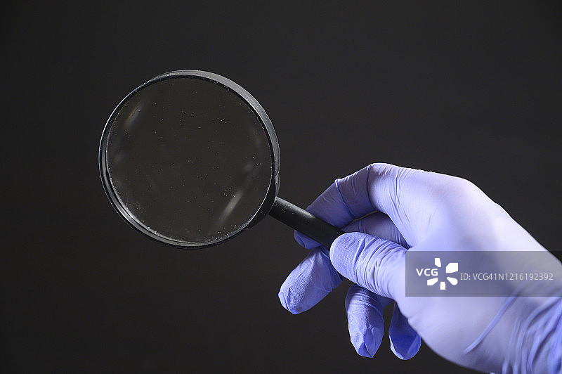 戴防护手套的手拿着放大镜图片素材