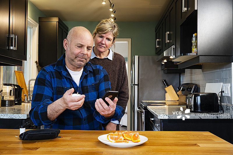 一位中年糖尿病患者在他的女伴的支持下检查血糖图片素材
