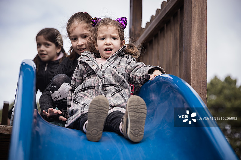 女孩们坐在雪橇上，一个小女孩害怕滑梯图片素材