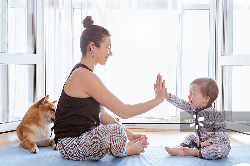 母亲和男婴在家训练，在笔记本电脑上看视频，柴犬在附近睡觉图片素材