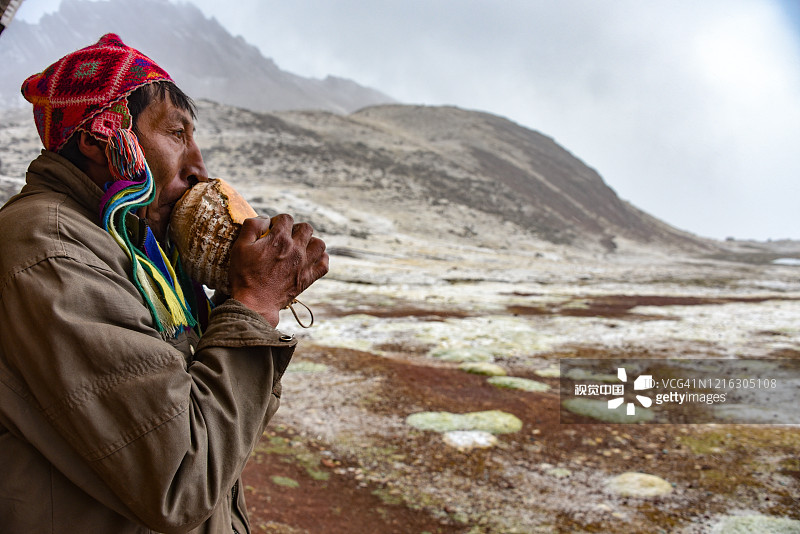 秘鲁库斯科附近安第斯山脉吹海螺的克丘亚族男人图片素材