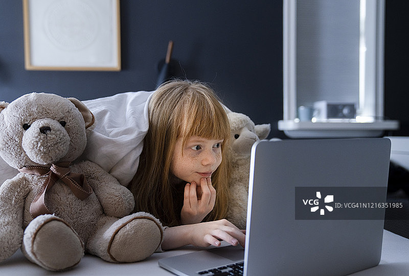 女孩在舒适的卧室里用电脑观看视频图片素材