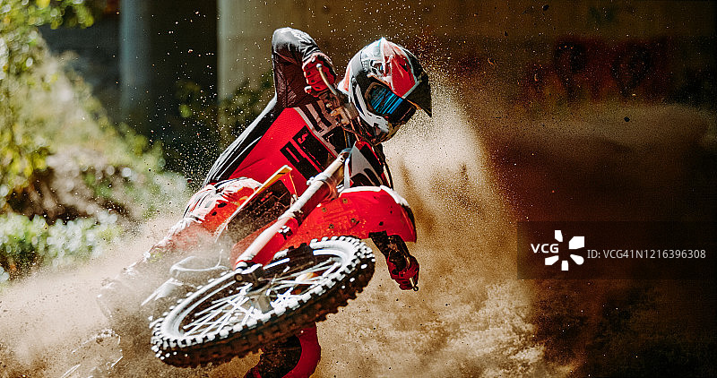 身穿红色运动服的摩托车越野车手在森林泥泞赛道上比赛图片素材