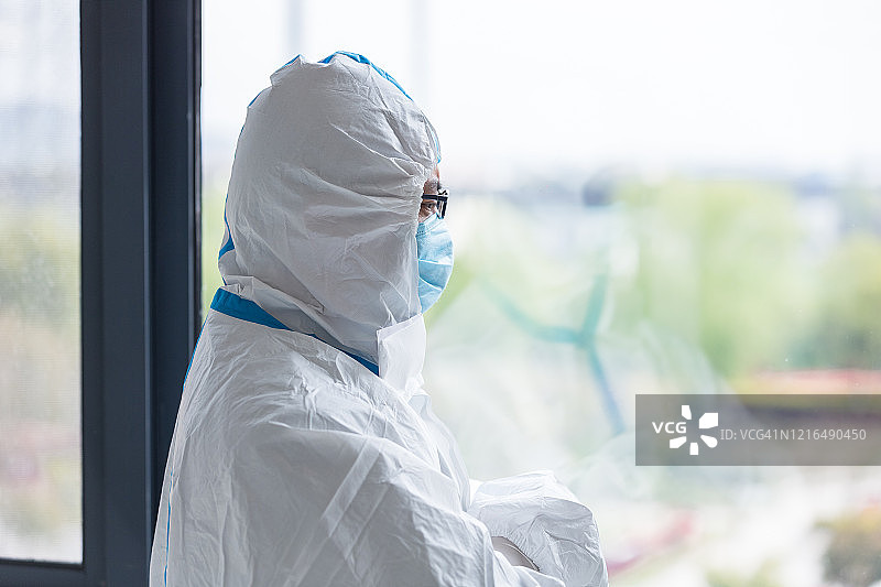 休息期间，身穿防护服的医生看着窗外图片素材