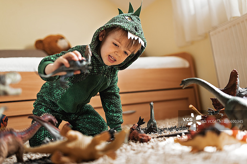 穿着恐龙服装玩恐龙的可爱幼儿图片素材
