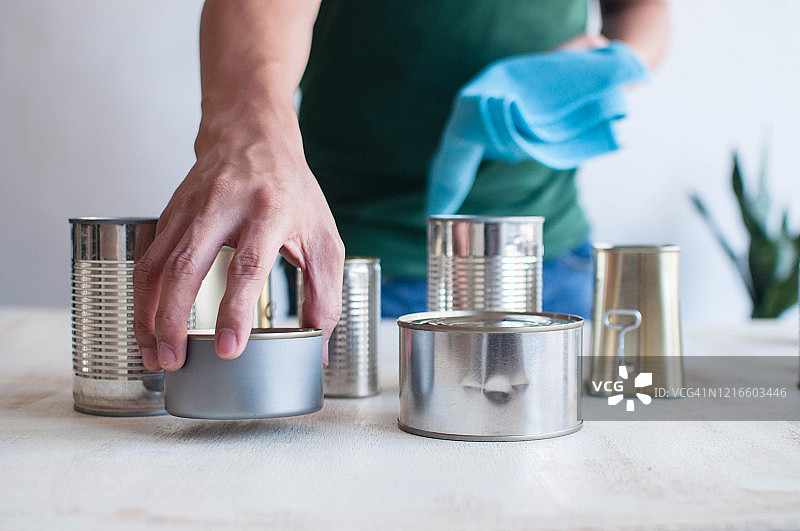 年轻东南亚男人在家中消毒罐装食品图片素材
