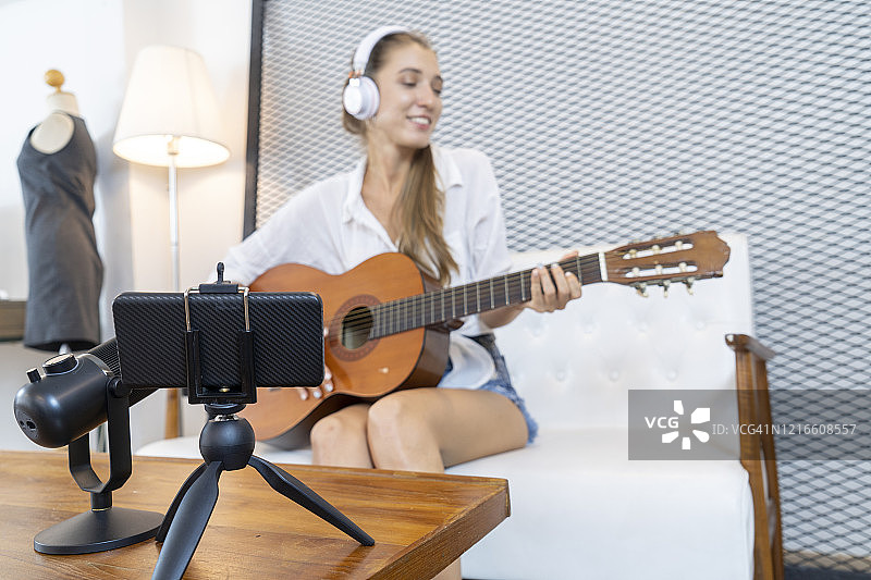 女博主创作音乐Vlog内容，白人女性在客厅弹奏吉他图片素材