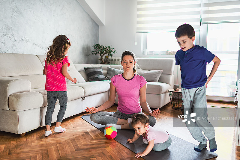 在嘈杂的孩子们奔跑时，年轻的母亲在冥想图片素材