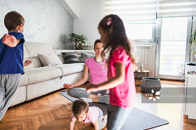 在嘈杂的孩子们奔跑时，年轻的母亲在冥想图片素材