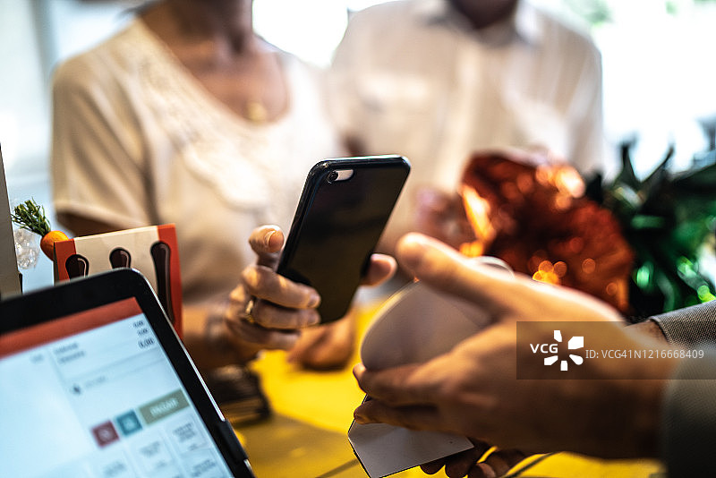 年长的女人在商店用手机支付图片素材