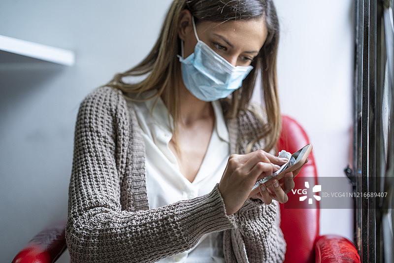 新冠疫情期间，女人正在消毒手机图片素材