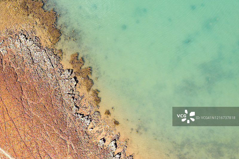 航拍：伸入蓝色热带海洋的岩石海岬图片素材