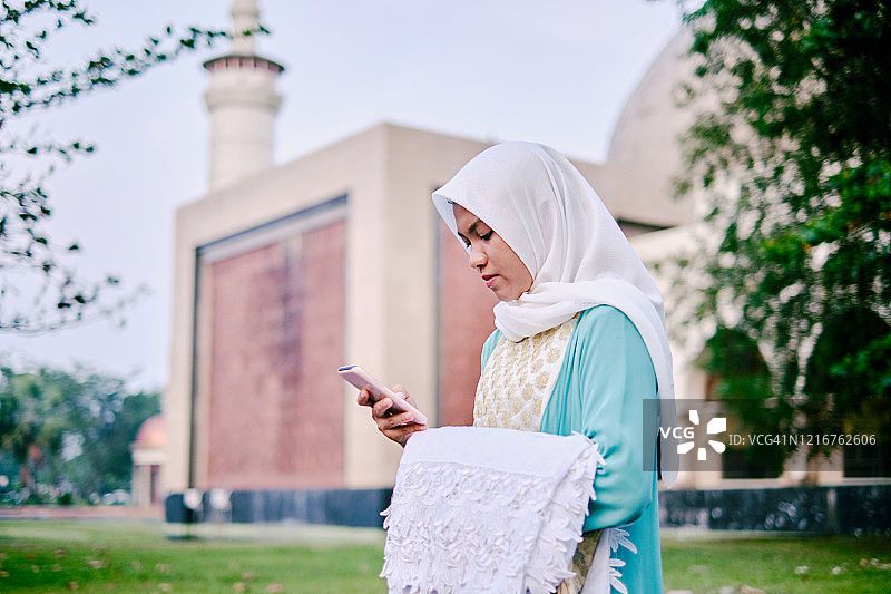 使用手机的年轻漂亮穆斯林女性图片素材