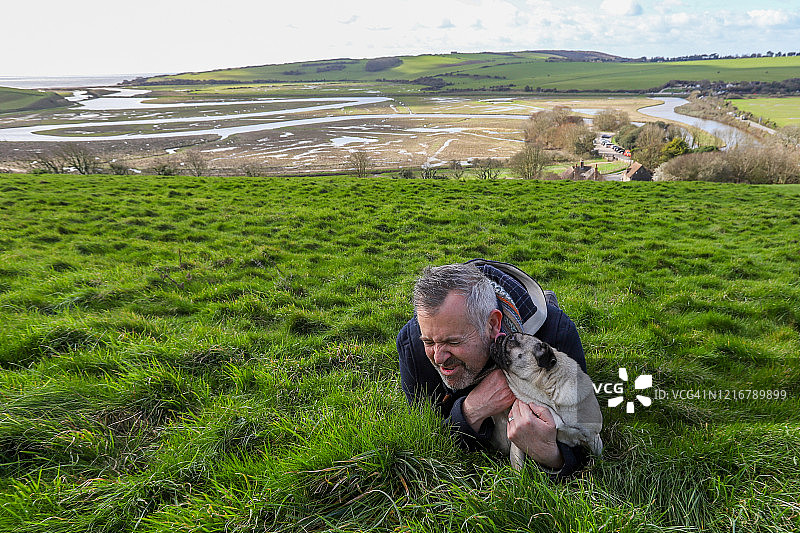 在卡克米尔港，巴哥犬舔舐男人的脸图片素材