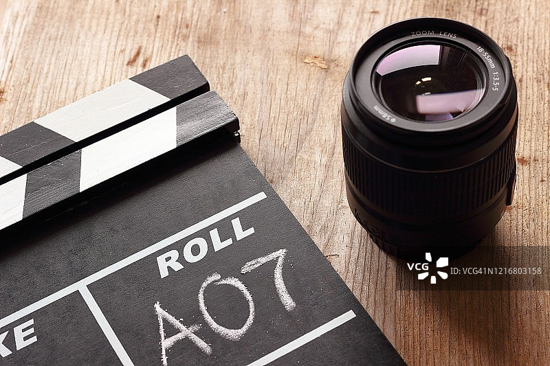 木质背景上的电影场记板和摄像机镜头图片素材