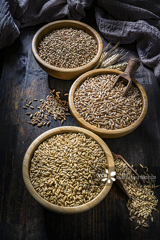 乡村厨房餐桌上的全麦荞麦、小麦粒和斯佩尔特小麦图片素材