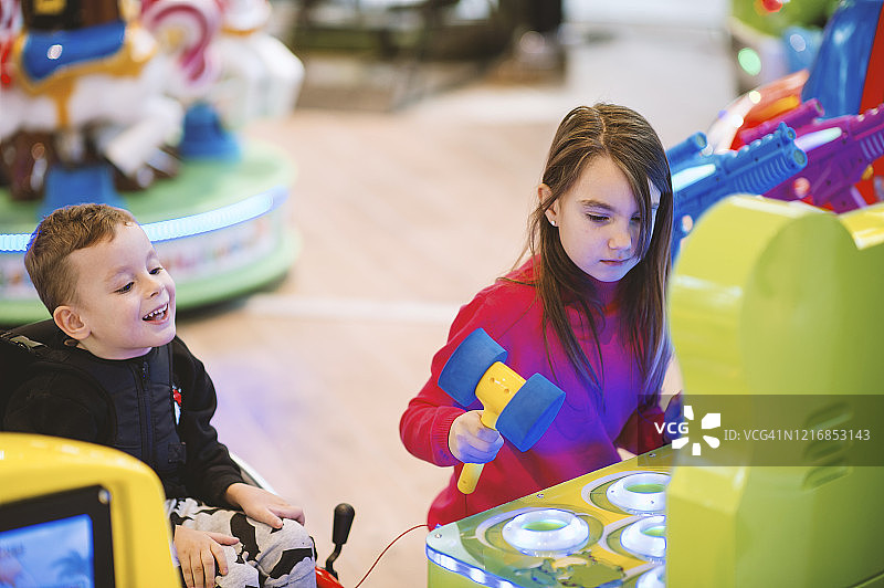 坐轮椅的男孩和在游乐厅里的女孩图片素材