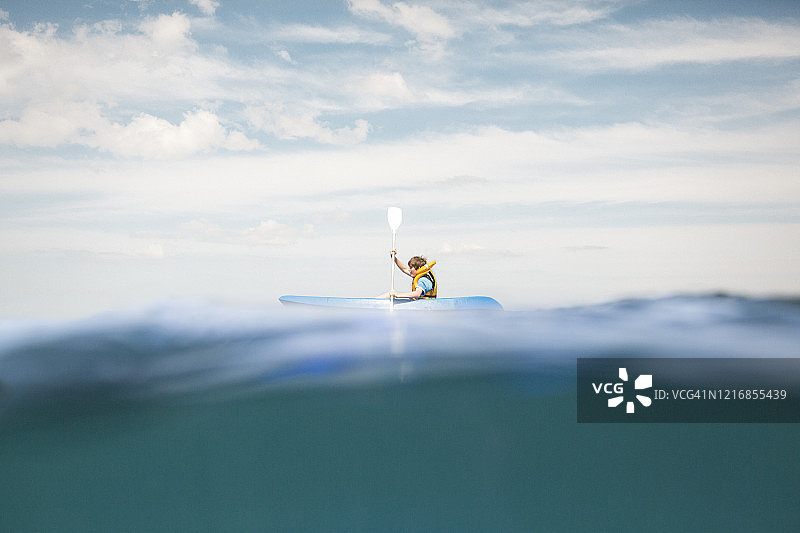 男孩在海上划独木舟图片素材