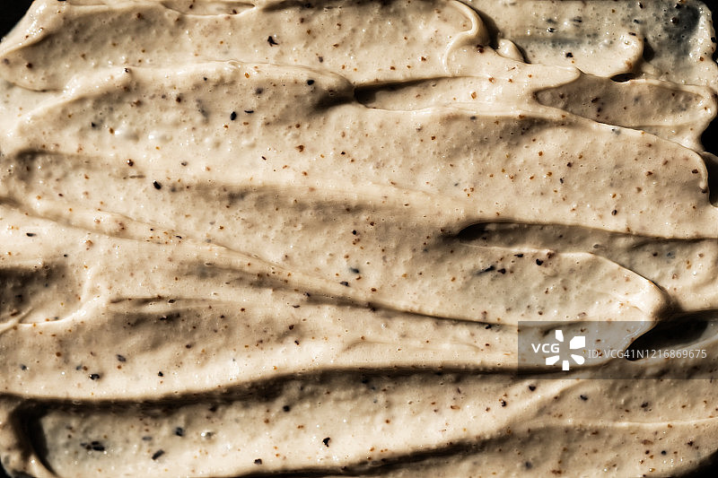 黑色背景下的化妆品磨砂膏质地，含咖啡和蜂蜜的面部和身体磨砂膏，有机美容概念图片素材