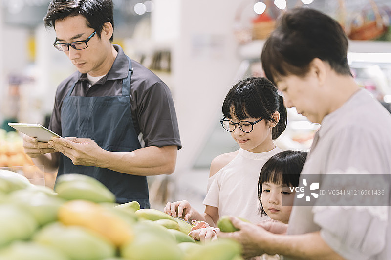 中国店员向祖孙三人介绍芒果图片素材
