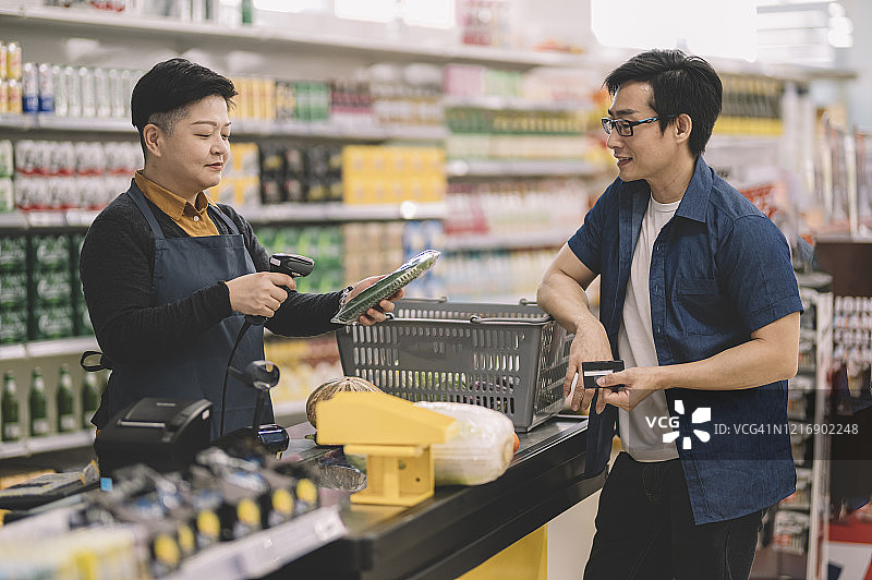 中国女收银员在收银台扫描顾客的商品图片素材
