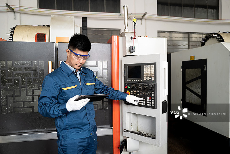 工程师在数控机床前查看数字平板电脑图片素材
