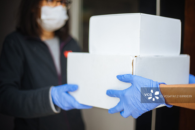 戴防护口罩的快递员向客户派送包裹图片素材