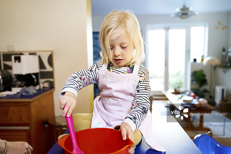女孩在家烘焙，在厨房台面上搅拌蛋糕混合物图片素材