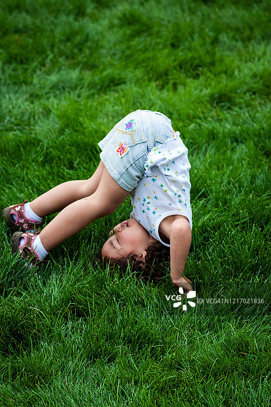 在草地上翻跟头的年轻女孩图片素材