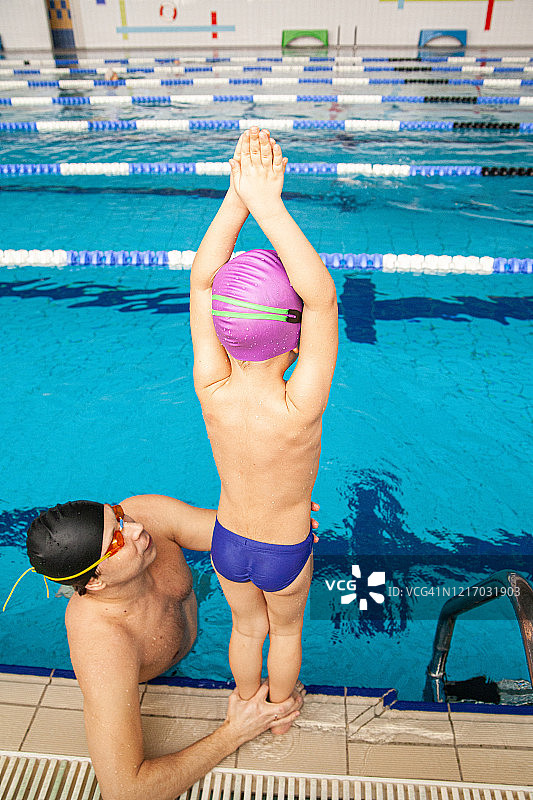 父亲教小儿子跳入水中，在游泳池练习图片素材