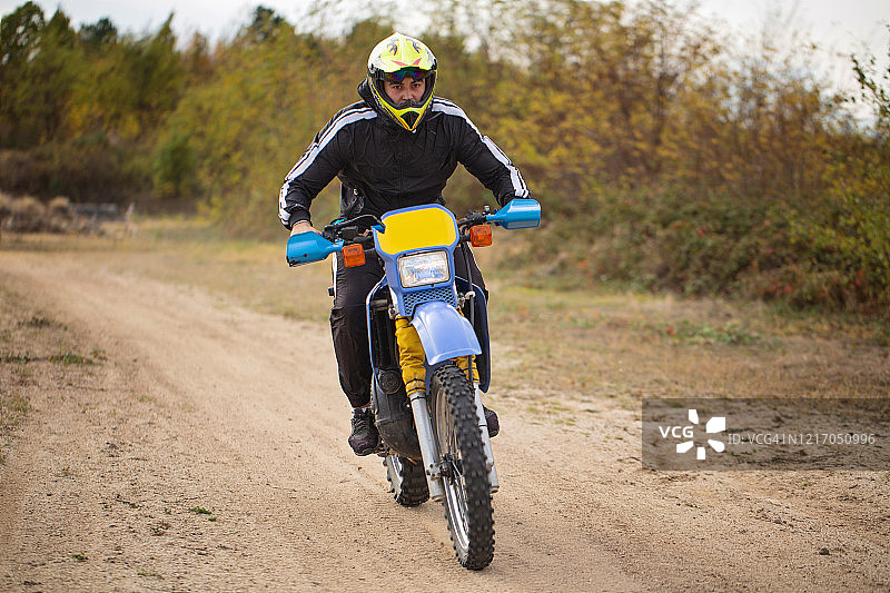 专注的摩托车越野赛车手在土路上行驶图片素材