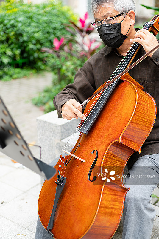 戴着医用口罩演奏大提琴的年长男人图片素材