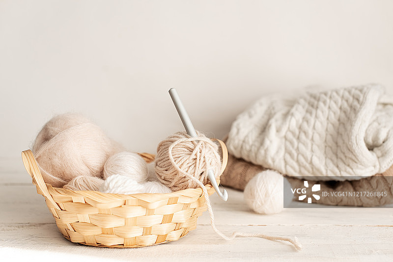 老式针织针、剪刀和纱线在木凳上的旧金属丝篮子里，柔焦静物照片图片素材