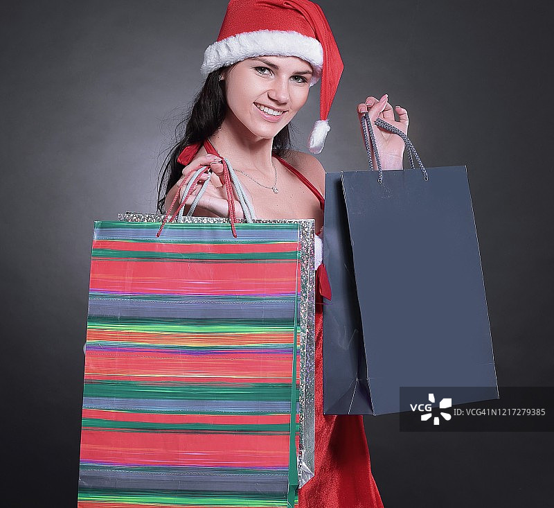 穿着圣诞老人服装，拿着圣诞袜的快乐年轻女人图片素材