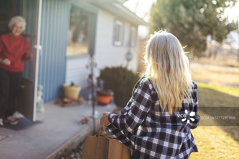 疫情期间中年女人送杂货给老年女人保持社交距离图片素材