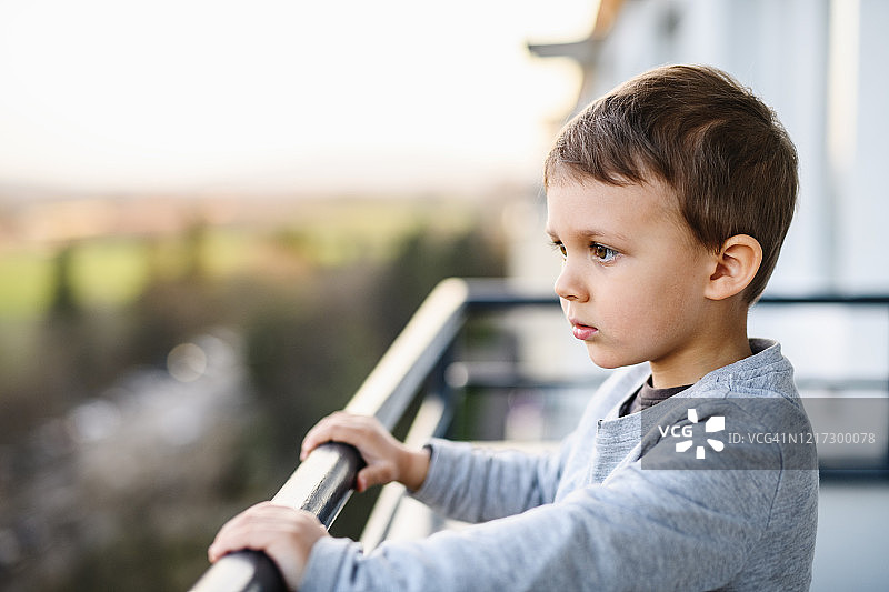 小男孩在家的阳台上，隔离和封锁概念图片素材