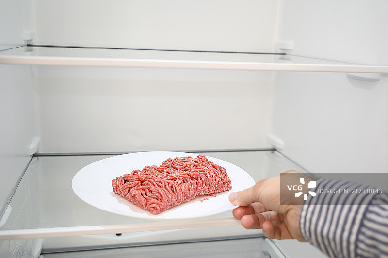 男人从冰箱里拿出一盘肉末图片素材