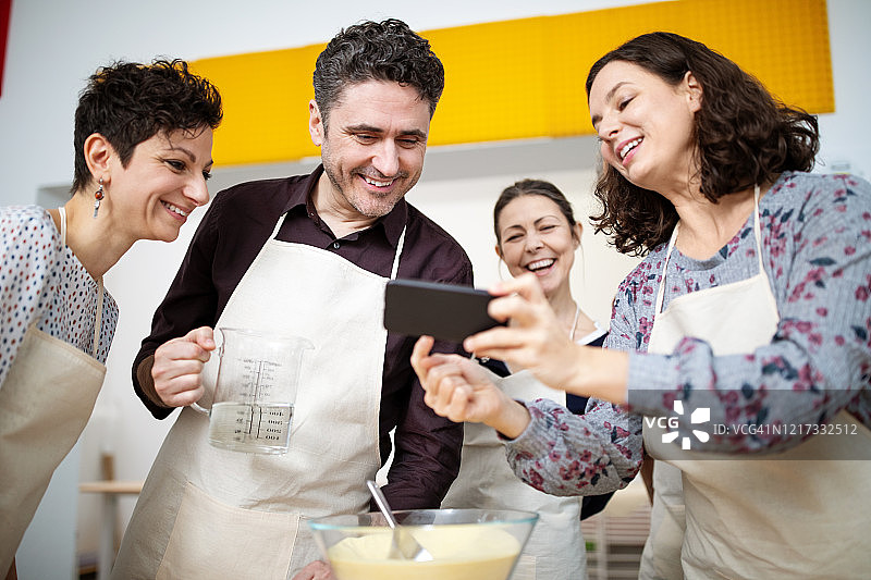 在烹饪工作室向朋友展示照片的女人图片素材